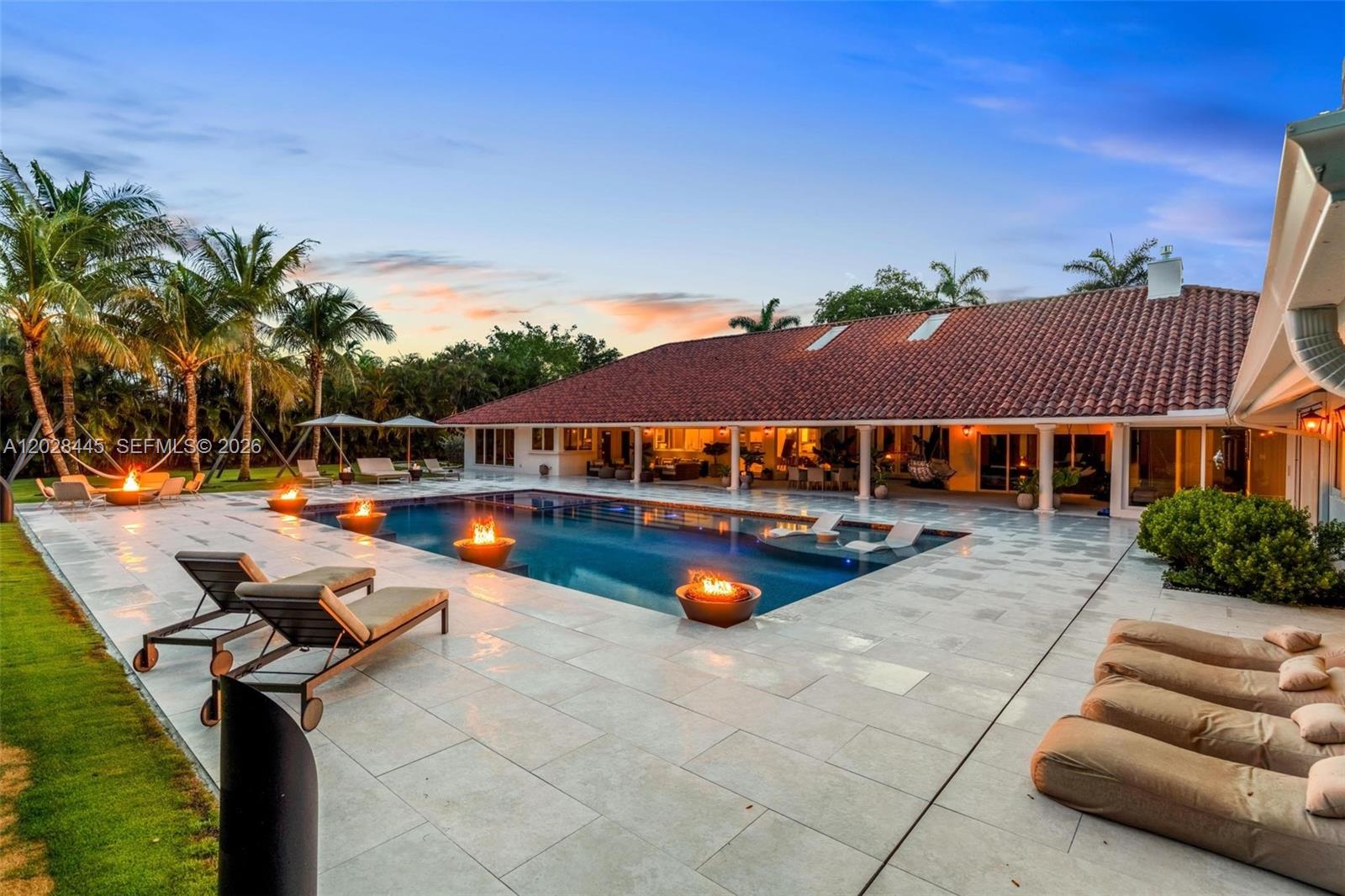 A backyard features a swimming pool with fire bowls, lounge chairs, and a covered patio — 8251 Old Cutler Rd, Coral Gables FL 33143, CORAL GABLES, FL