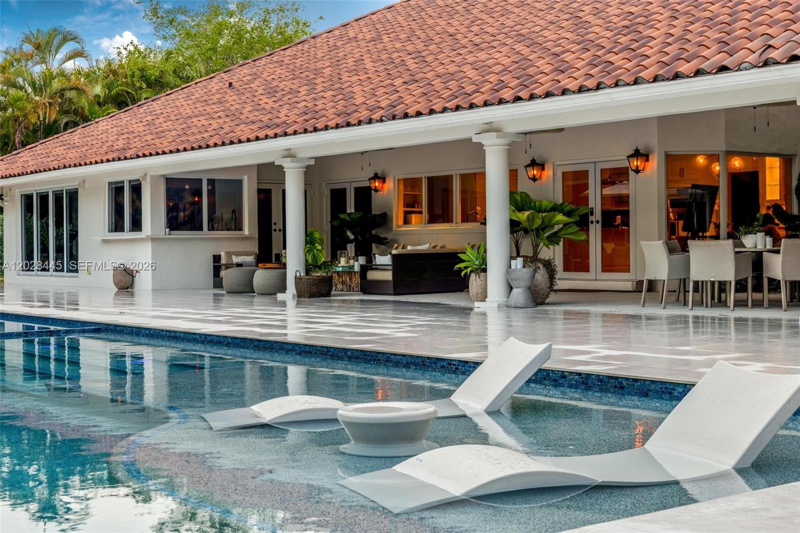 A swimming pool with lounge chairs sits in front of a house with a tiled roof — 8251 Old Cutler Rd, Coral Gables FL 33143, CORAL GABLES, FL