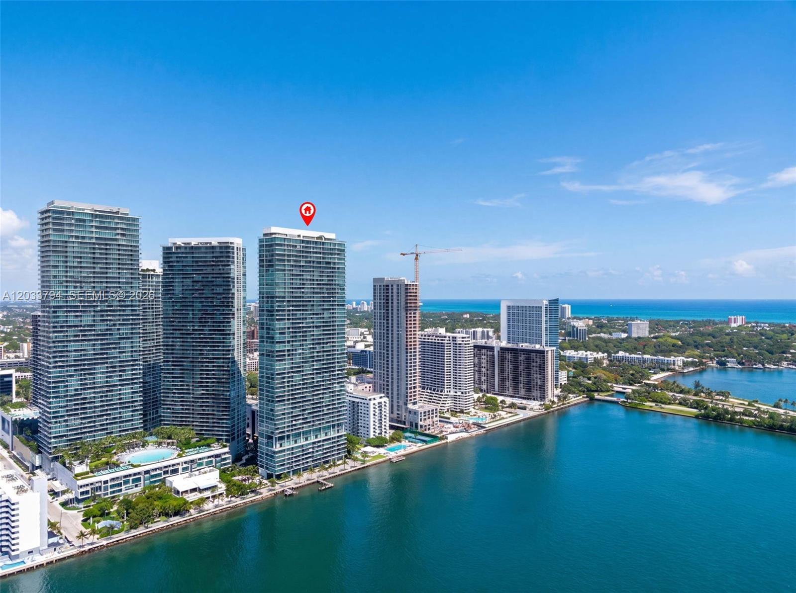 An aerial view shows several high-rise residential towers situated along a waterfront — 3131 NE 7th Ave # 2605, Miami FL 33137, MIAMI, FL