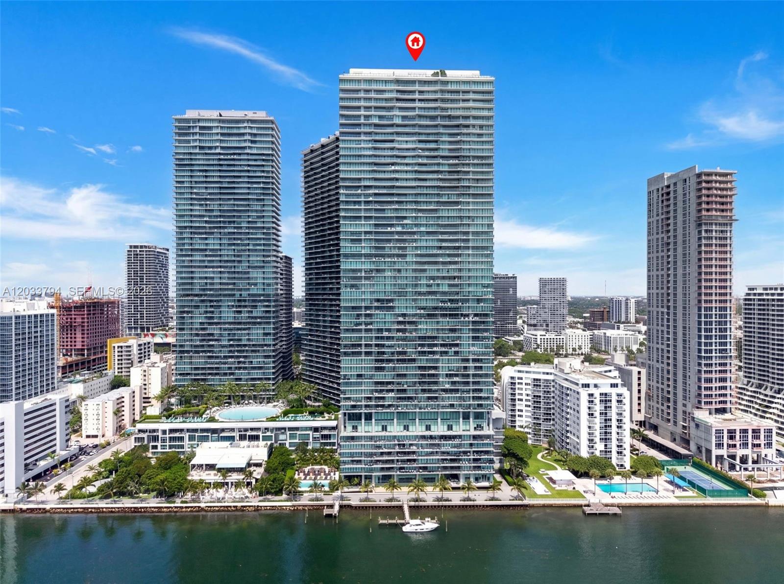 An aerial view shows several high-rise residential buildings along a waterfront with a boat docked — 3131 NE 7th Ave # 2605, Miami FL 33137, MIAMI, FL