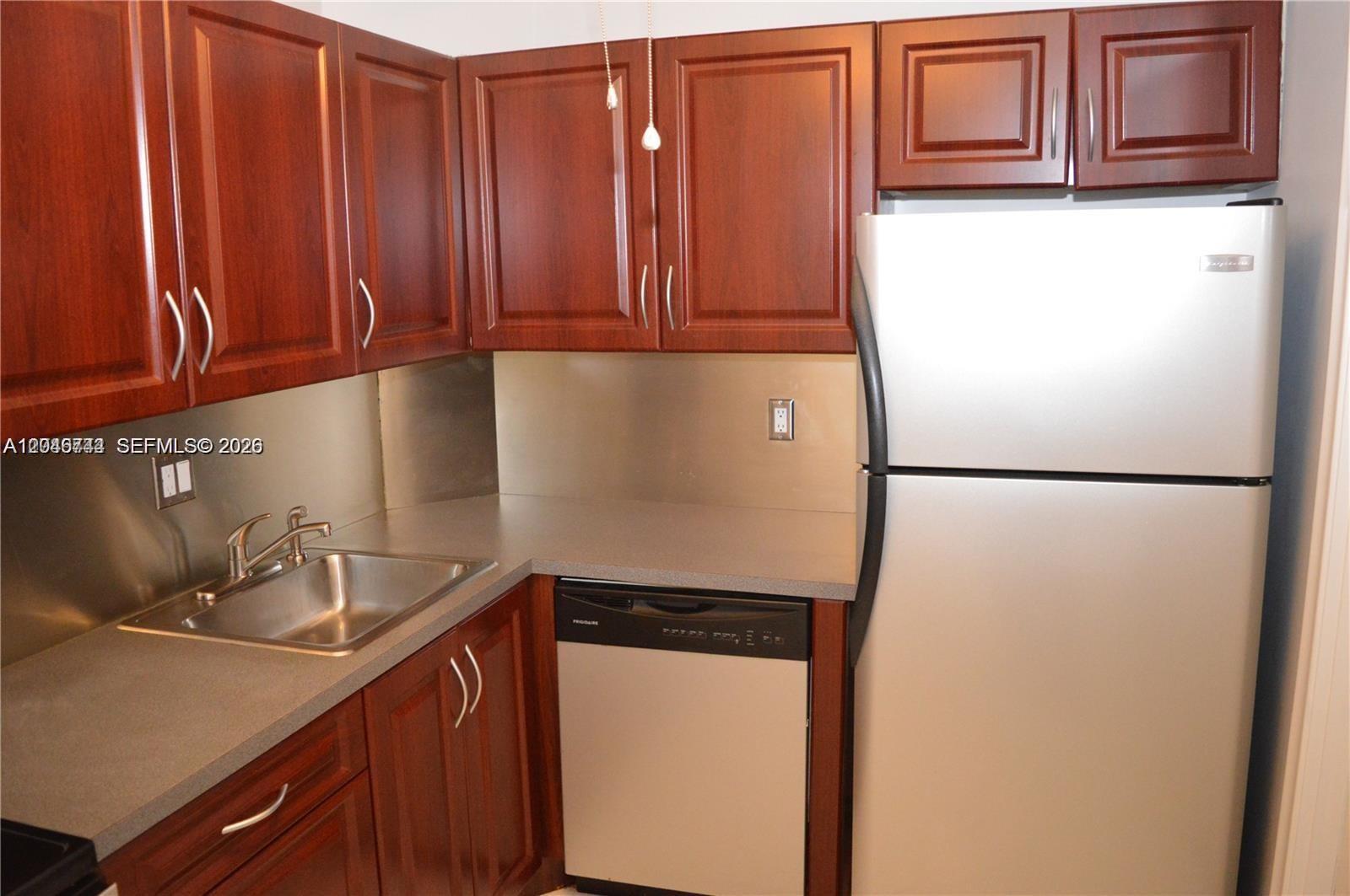 A kitchen features dark wood cabinets, stainless steel appliances, a grey countertop, and a sink — 9 NE 19th Ct # 204C, Wilton Manors FL 33305, WILTON MANORS, FL