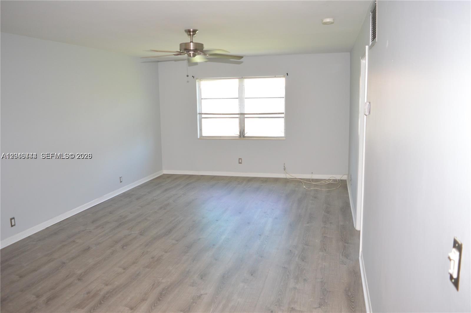 An empty room features light gray walls, wood-look flooring, a ceiling fan, and a window — 9 NE 19th Ct # 204C, Wilton Manors FL 33305, WILTON MANORS, FL