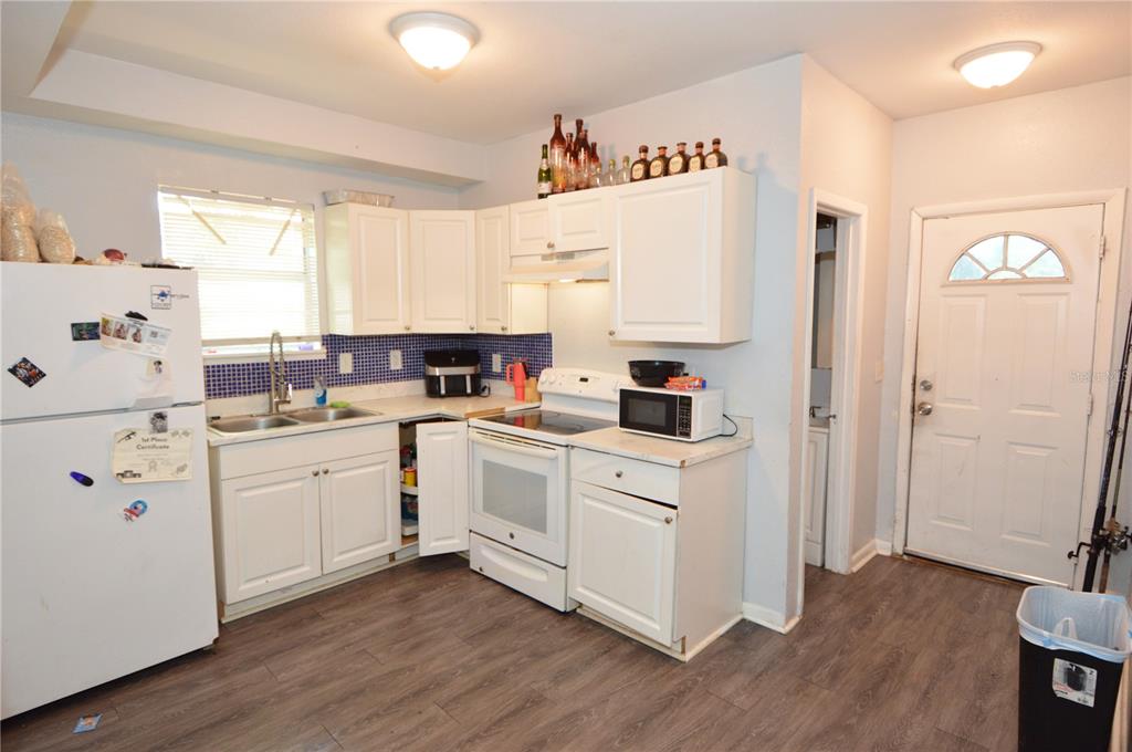 A kitchen with white cabinets, a white stove, a refrigerator, and blue tiled backsplash — 811 18TH AVENUE S, ST PETERSBURG, FL