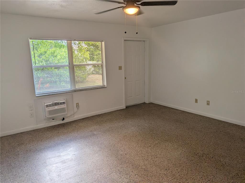 An empty room features white walls, carpeted flooring, a window air conditioner, and a ceiling fan — 2461 44, OCALA, FL