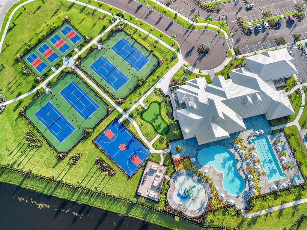 Aerial view of a community center featuring tennis courts, a basketball court, and swimming pools — 15131 SUNNY DAY DRIVE, BRADENTON, FL