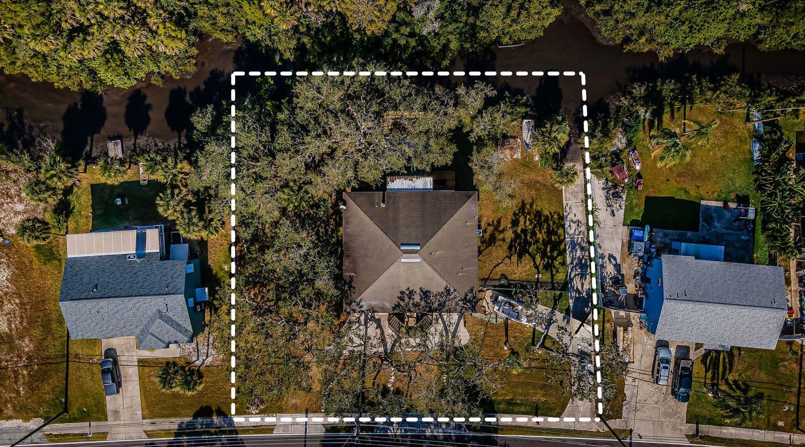 An aerial view shows a house with a hipped roof surrounded by trees and landscaping — 5127 Bay Boulevard, FL 34668, FL
