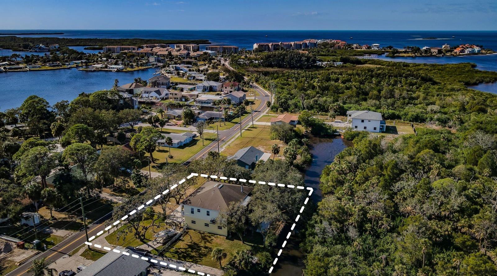 An aerial view shows a yellow house with a dashed outline on a wooded lot — 5127 Bay Boulevard, FL 34668, FL