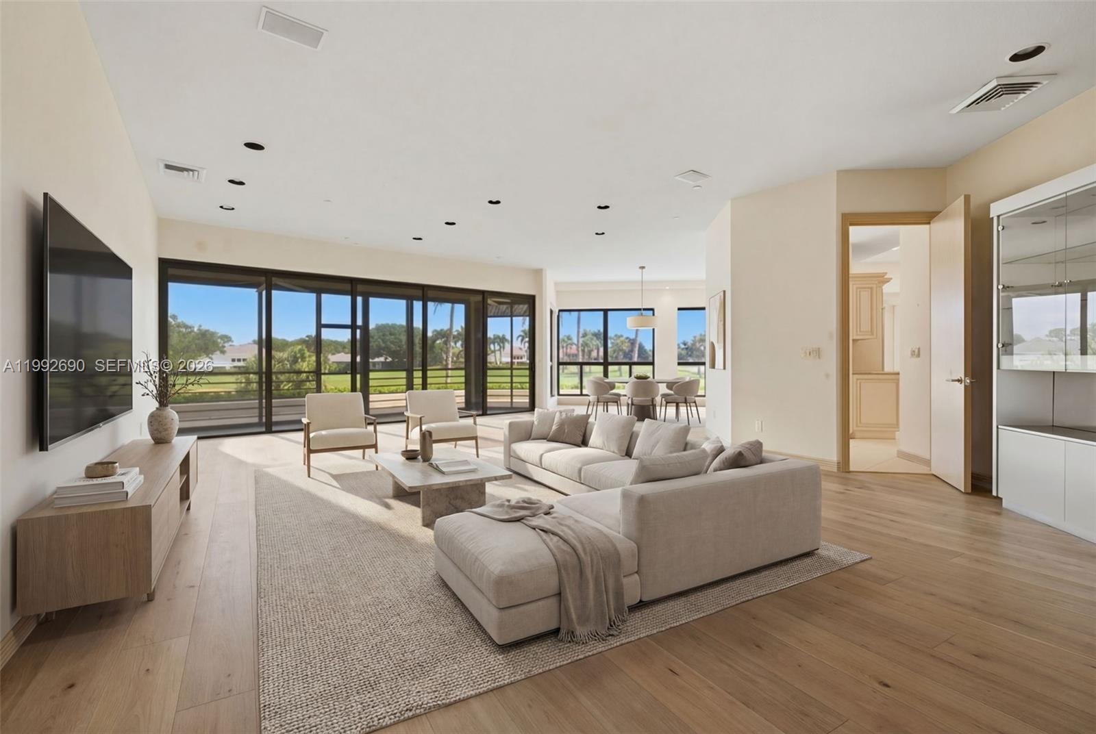 A spacious living room features light wood floors, a large sectional, and floor-to-ceiling glass doors — 7383 Orangewood Ln # 301, Boca Raton FL 33433, BOCA RATON, FL