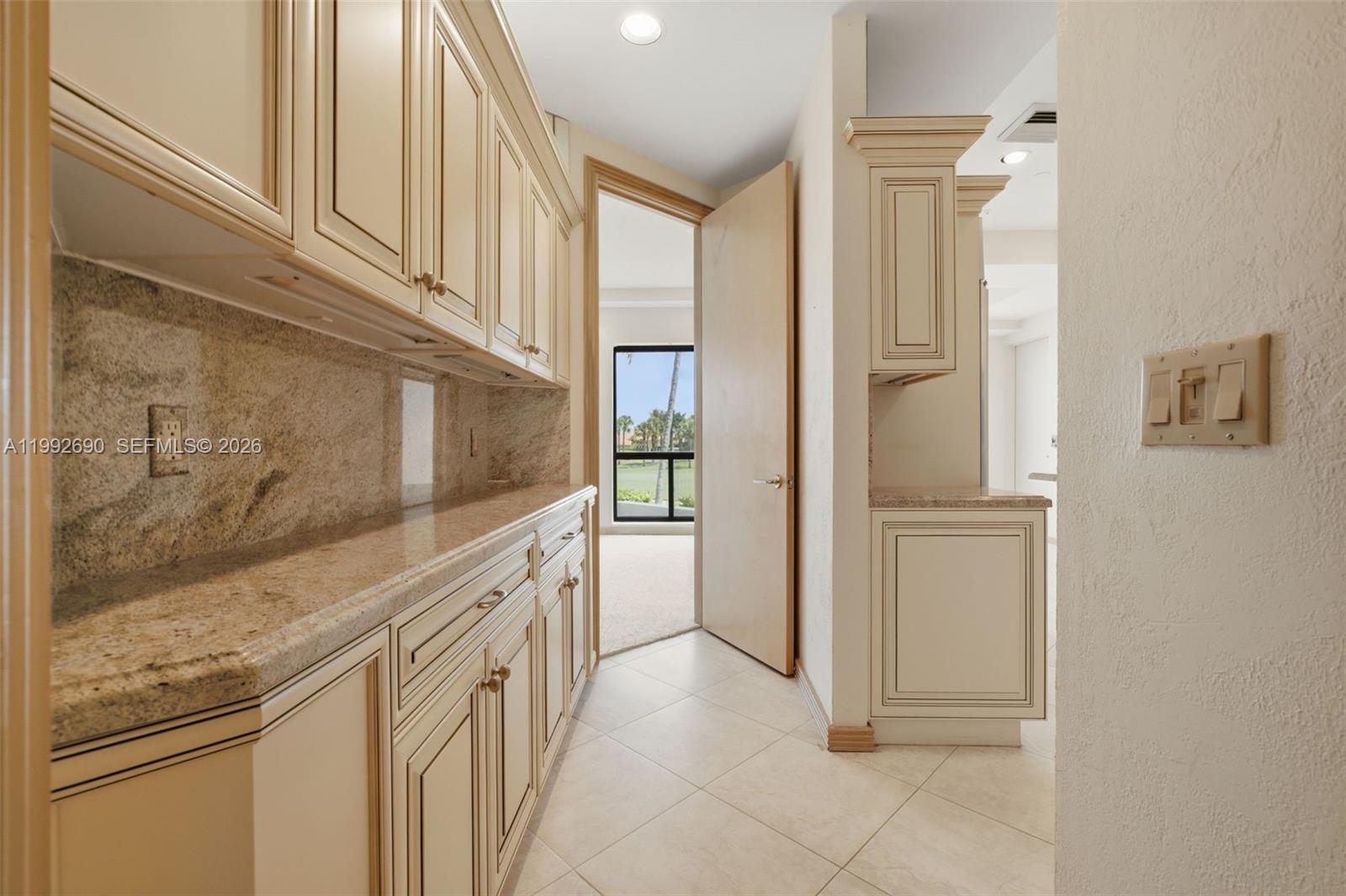 A hallway features cream-colored cabinetry, granite countertops, tile flooring, and a doorway to a room — 7383 Orangewood Ln # 301, Boca Raton FL 33433, BOCA RATON, FL