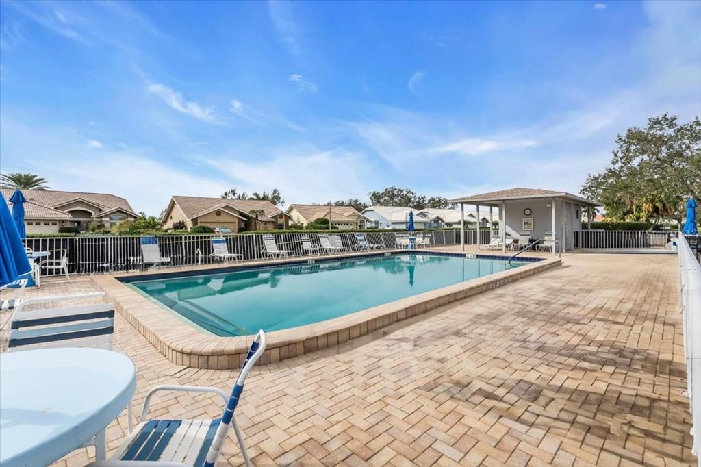 A rectangular swimming pool with a paved deck and a covered patio area — 6713 STONE RIVER ROAD UNIT 206, BRADENTON, FL