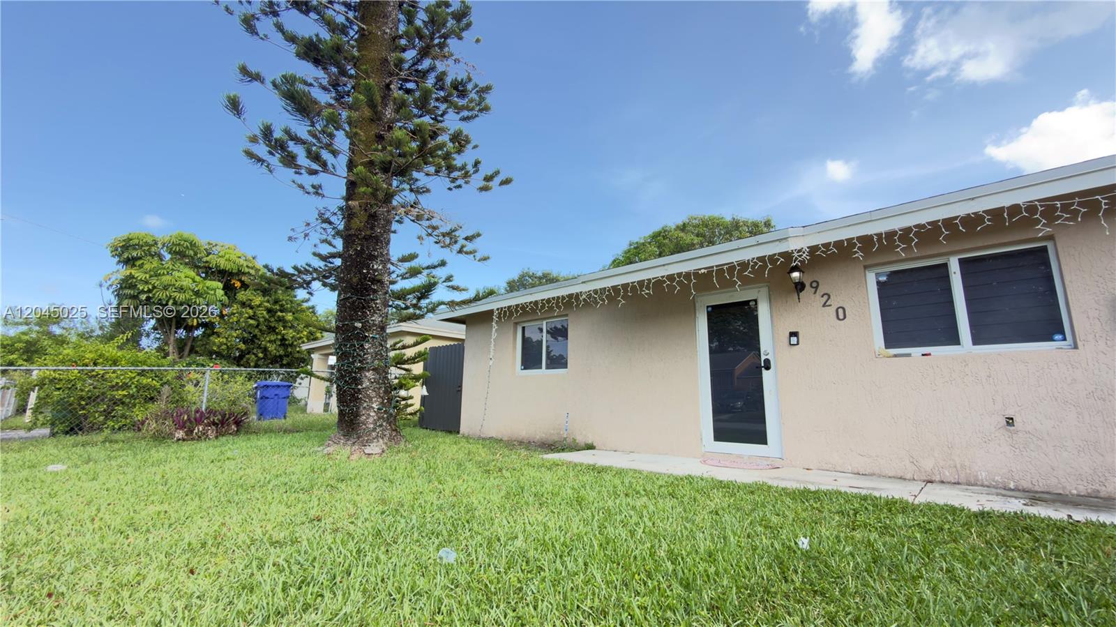 A single-story house with a beige stucco exterior and a tall pine tree in front — 920 NW 65th St, Miami FL 33150, MIAMI, FL