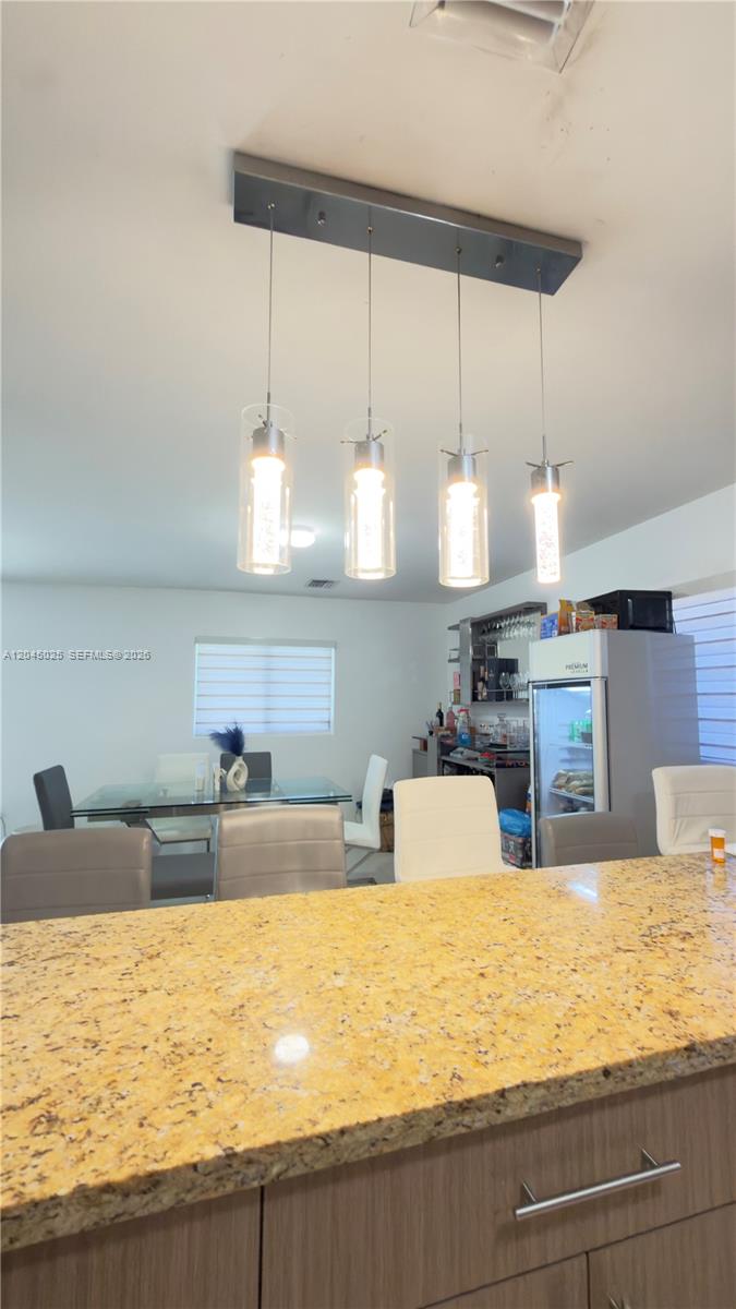 A kitchen island with a granite countertop sits in front of a dining area — 920 NW 65th St, Miami FL 33150, MIAMI, FL