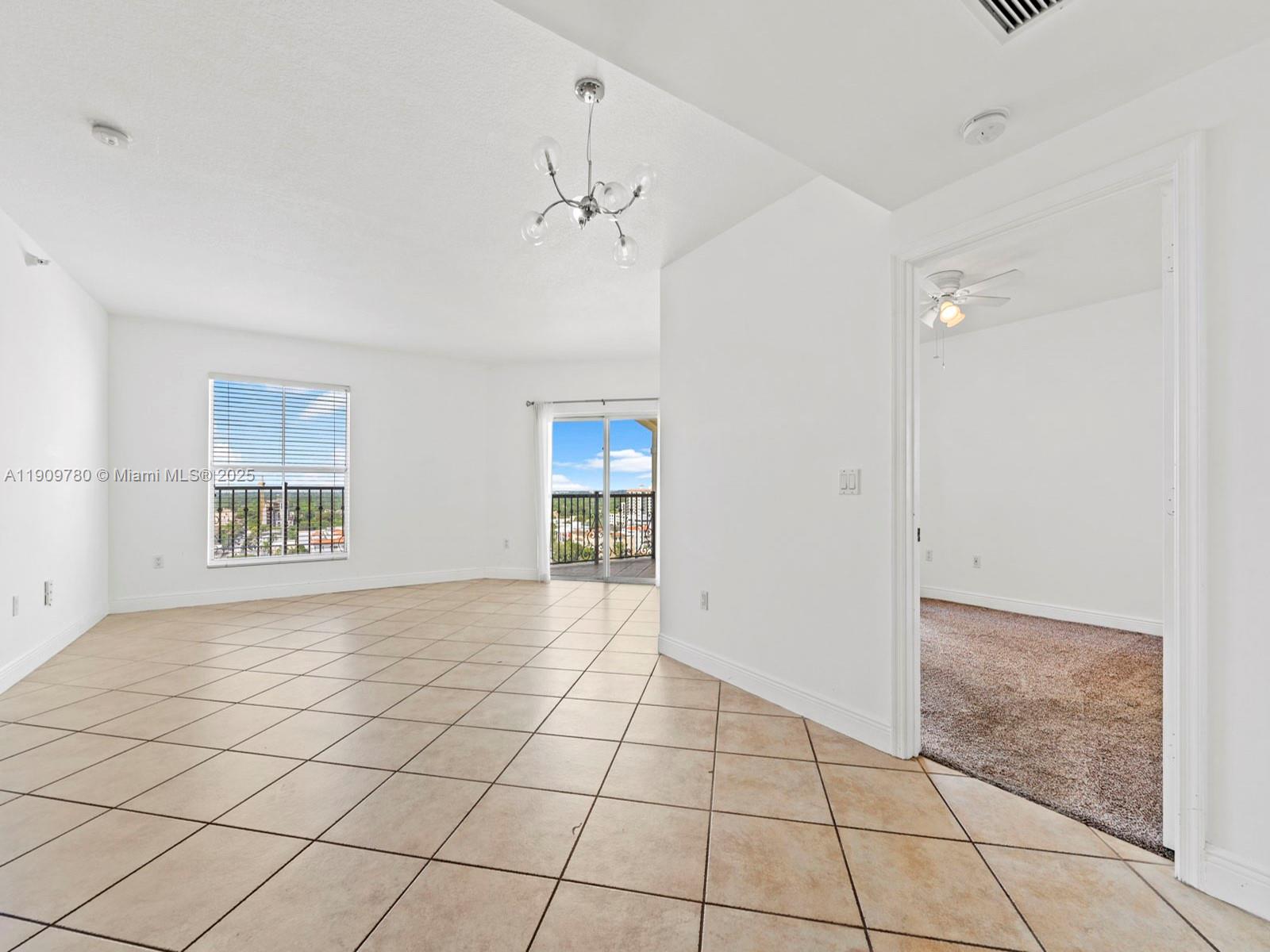 An empty living room with tile floors leads to a balcony through sliding glass doors — 1627 SW 37th Ave # 1103, Miami FL 33145, MIAMI, FL