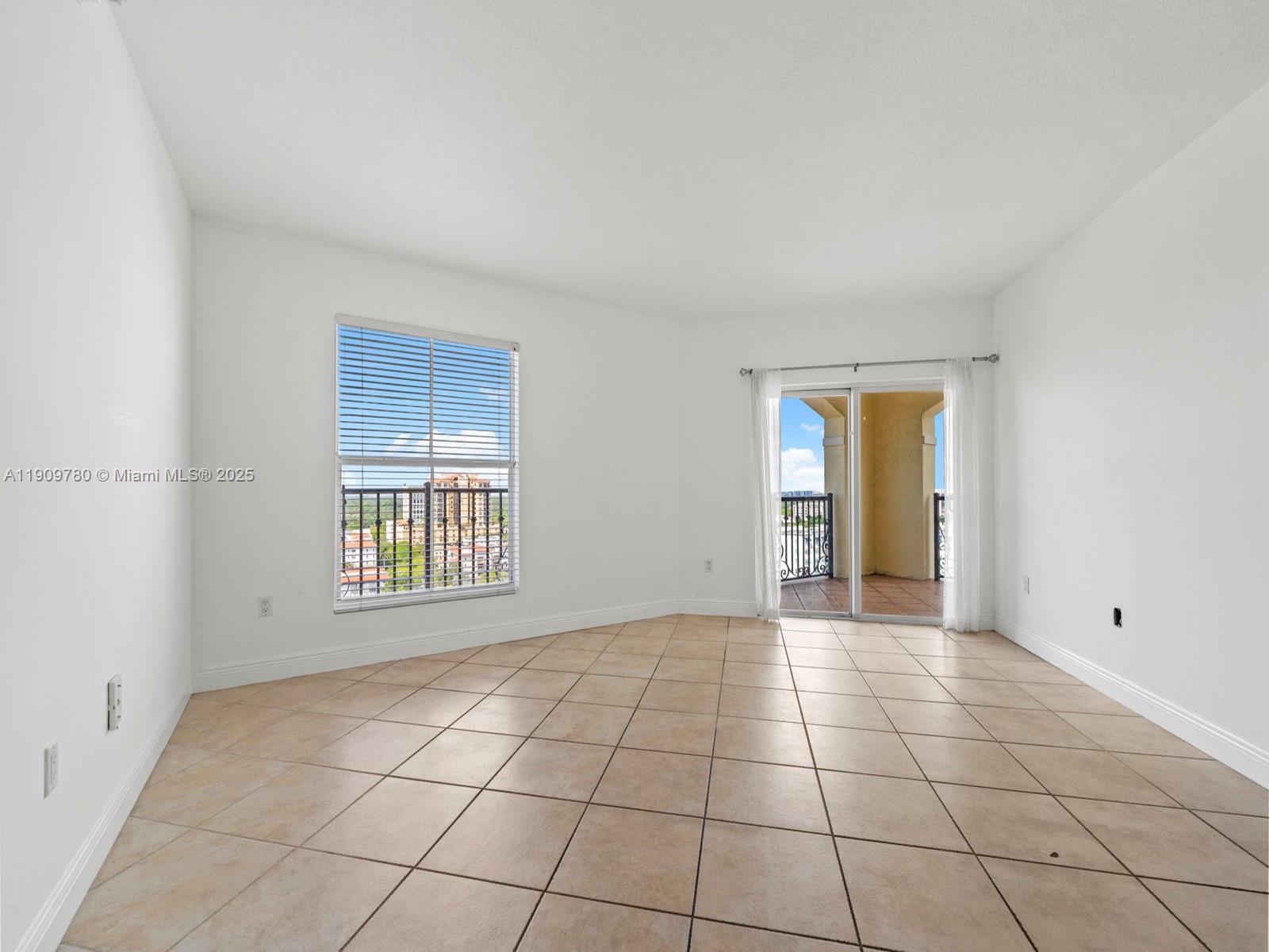 An empty room features beige tile flooring, white walls, a window, and a sliding glass door — 1627 SW 37th Ave # 1103, Miami FL 33145, MIAMI, FL