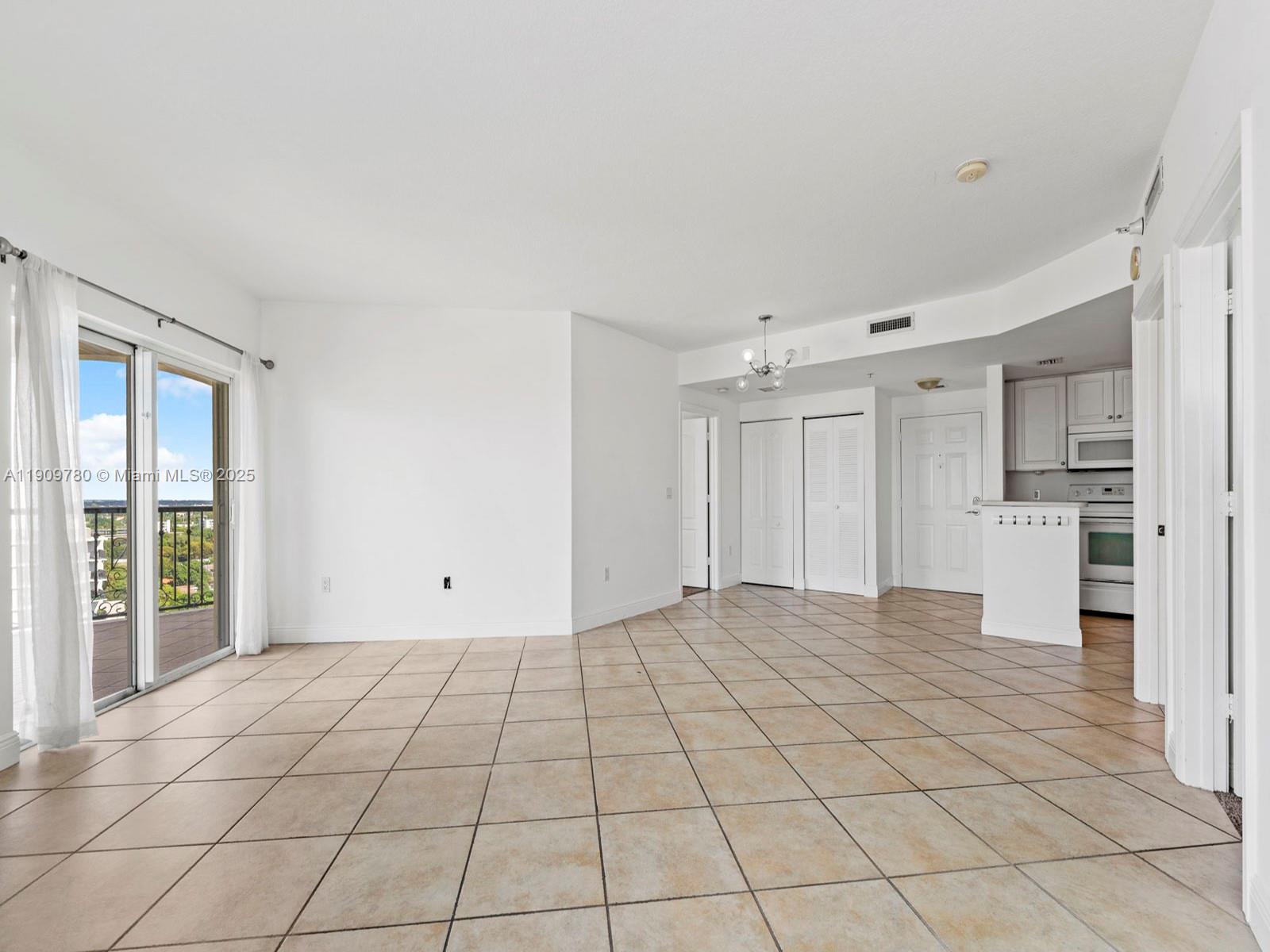 An open-concept living area features beige tile flooring, white walls, and a balcony with views — 1627 SW 37th Ave # 1103, Miami FL 33145, MIAMI, FL
