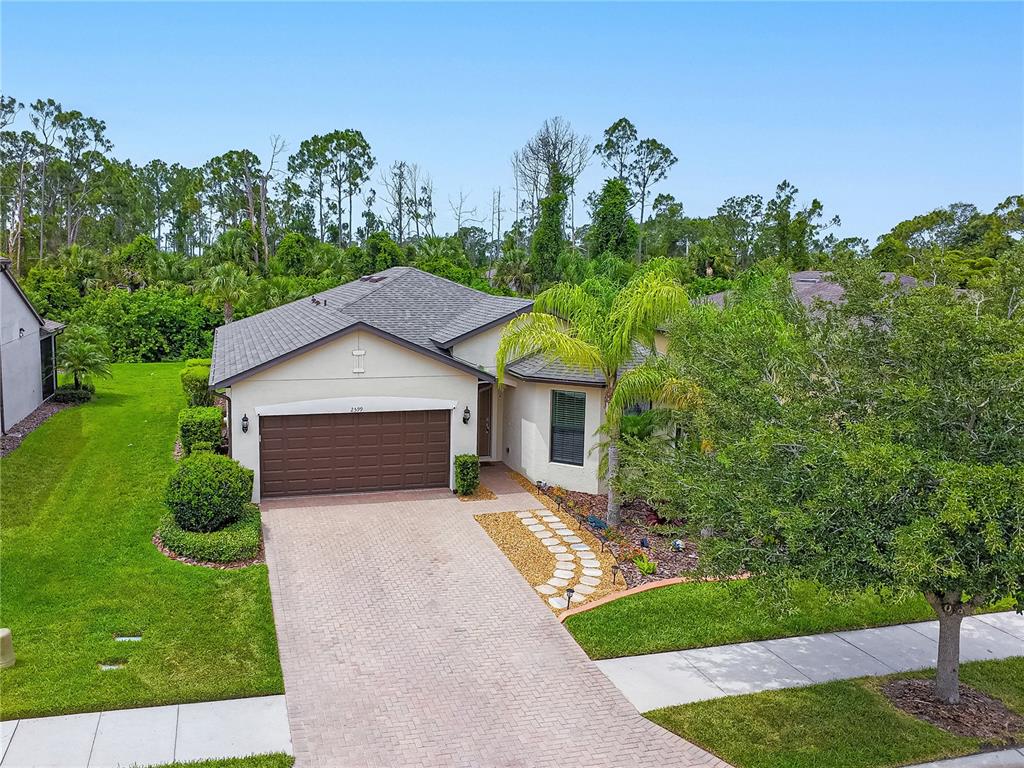 A single-story house with a brown garage door, paver driveway, and landscaped front yard — 2599 SHERMAN OAK DRIVE, NORTH PORT, FL