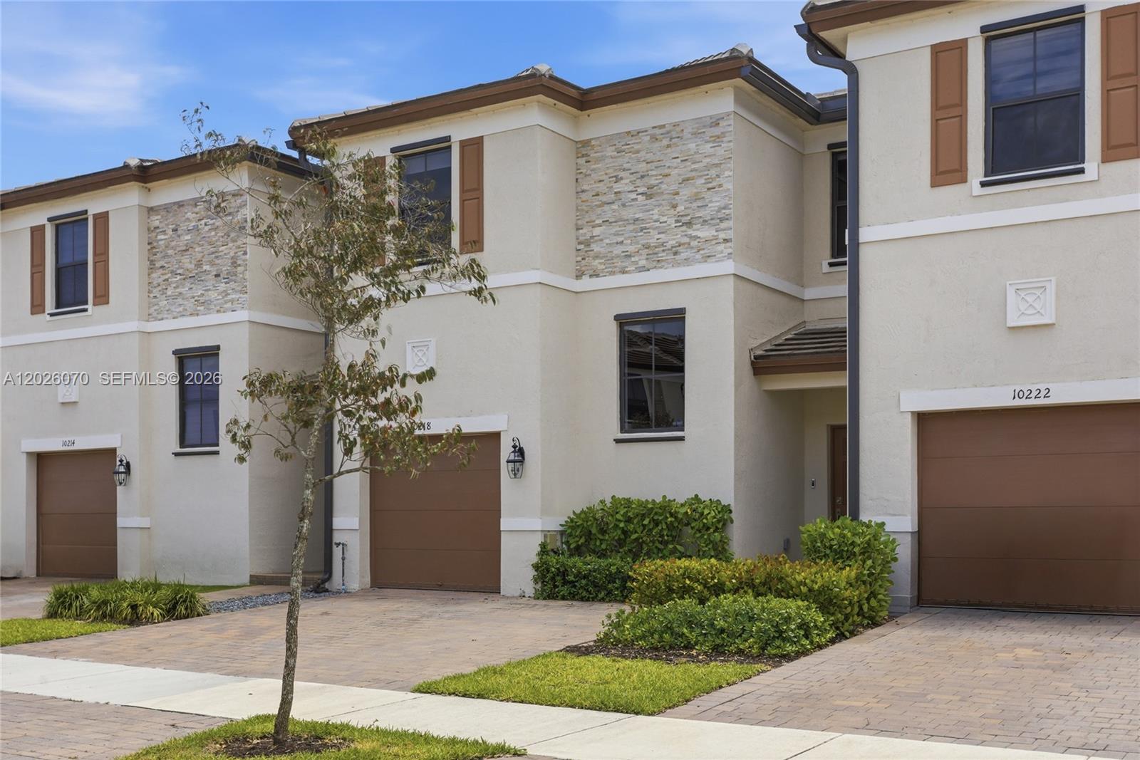 The exterior view shows three attached townhouses with beige stucco, stone accents, and brown garages — 10218 SW 231st Ln, Cutler Bay FL 33190, CUTLER BAY, FL
