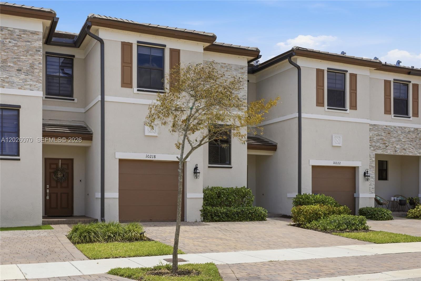 The exterior shows two adjacent townhouses with beige stucco walls, brown garage doors, and stone accents — 10218 SW 231st Ln, Cutler Bay FL 33190, CUTLER BAY, FL
