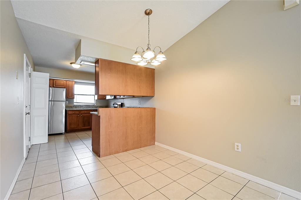 A dining area with tile flooring sits adjacent to a kitchen with wood cabinets — 224 COBALT DRIVE, KISSIMMEE, FL