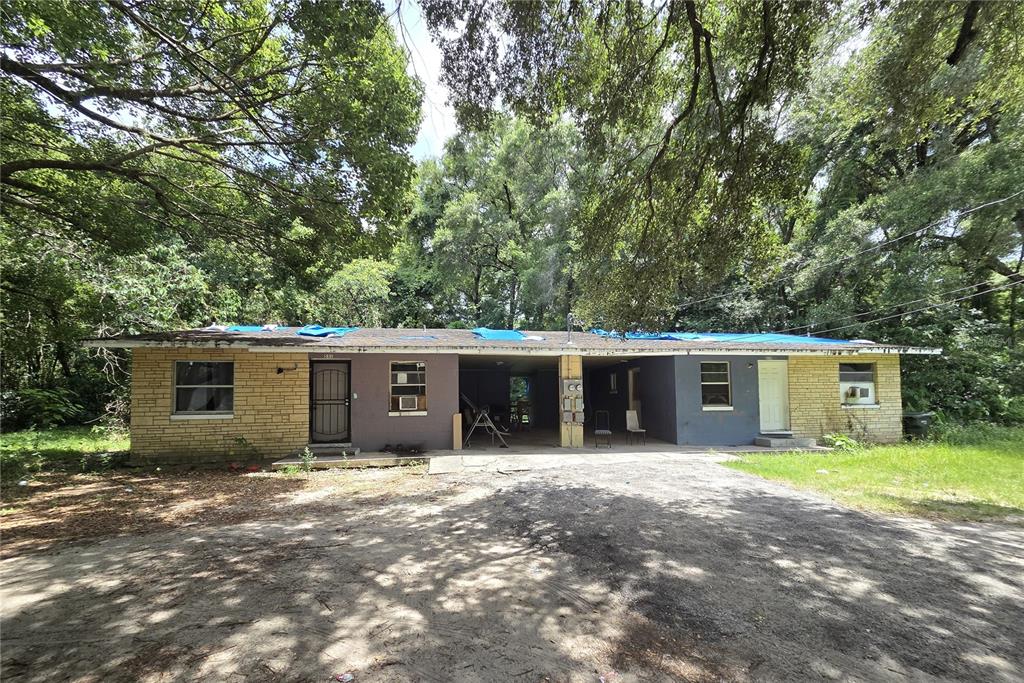 A single-story duplex with a brick and stucco exterior and blue tarps on the roof — 521-535 NW 19TH AVENUE, OCALA, FL