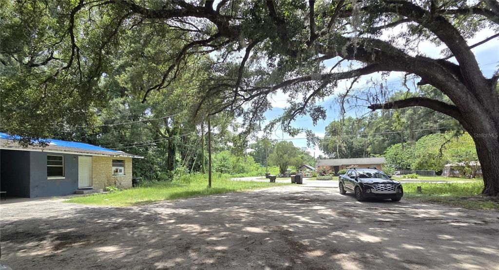 A gravel driveway leads to a small house under a large, moss-draped oak tree — 521-535 NW 19TH AVENUE, OCALA, FL