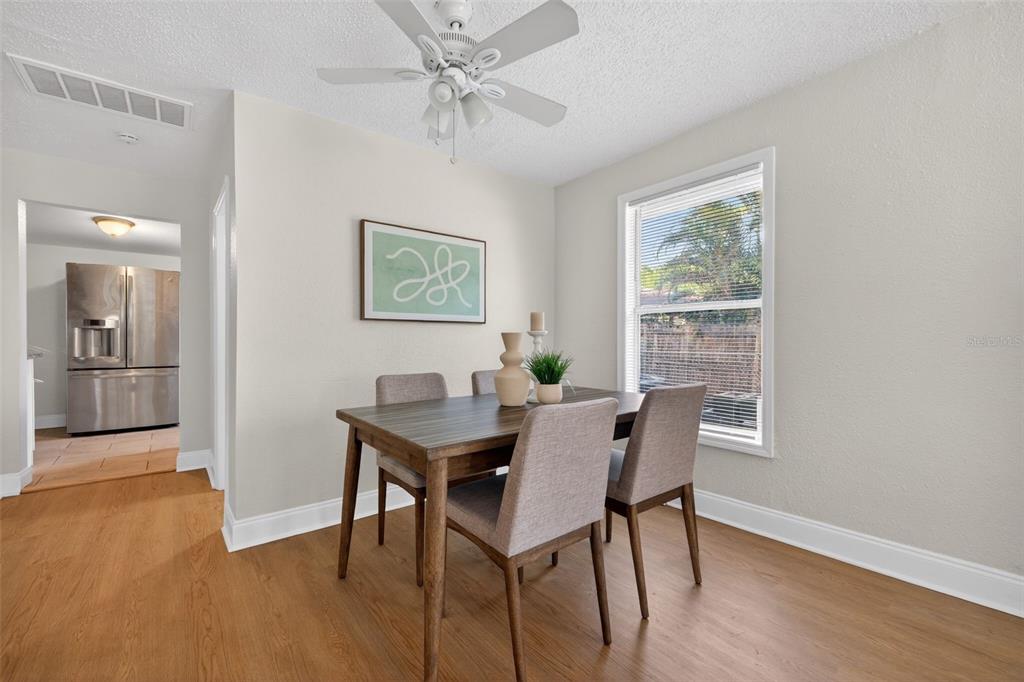 A dining room with wood-look flooring, a wooden table, four chairs, and a ceiling fan — 1777 28TH AVENUE N, ST PETERSBURG, FL