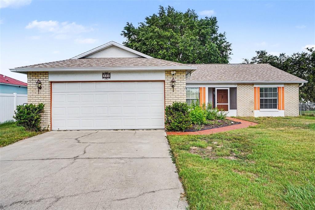 A single-story brick house with a two-car garage and a front walkway — 330 CORTEZ COURT, KISSIMMEE, FL