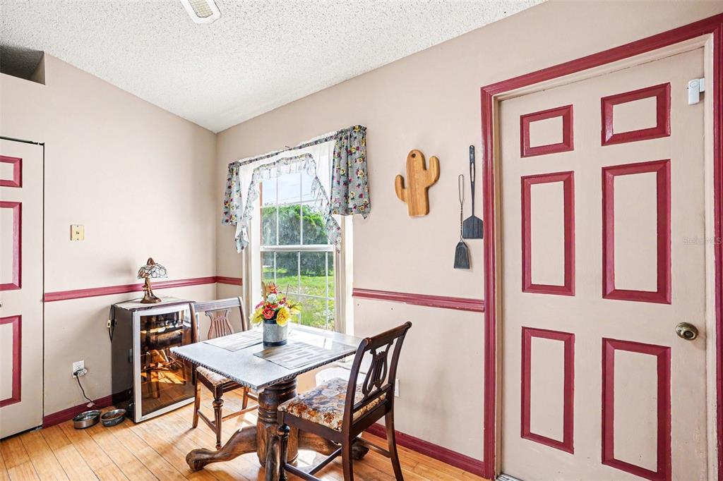A dining area features a small table, two chairs, a wine cooler, and red-trimmed doors — 330 CORTEZ COURT, KISSIMMEE, FL