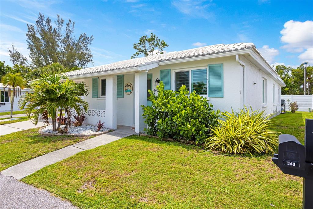 A white single-story house with teal shutters and a palm tree in the front yard — 546 SPANISH DRIVE S, LONGBOAT KEY, FL