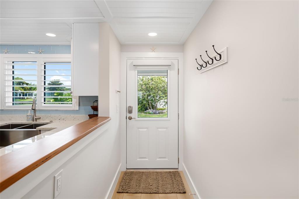 A white door with a window leads into a kitchen area with a wooden counter — 546 SPANISH DRIVE S, LONGBOAT KEY, FL