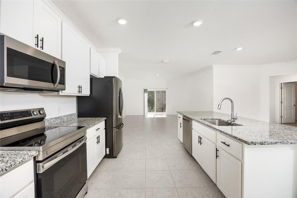 A kitchen with white cabinets, granite countertops, stainless steel appliances, and tile flooring — 15451 NW 121ST PLACE, ALACHUA, FL