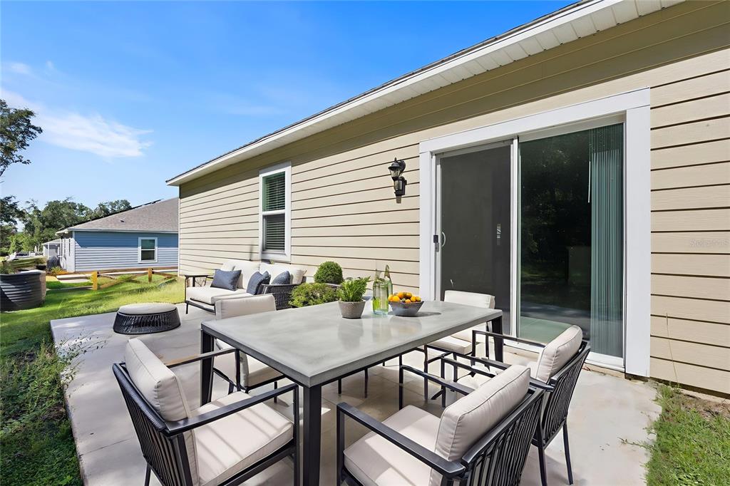 A patio features a dining set and sofa against the beige siding of a house — 15451 NW 121ST PLACE, ALACHUA, FL