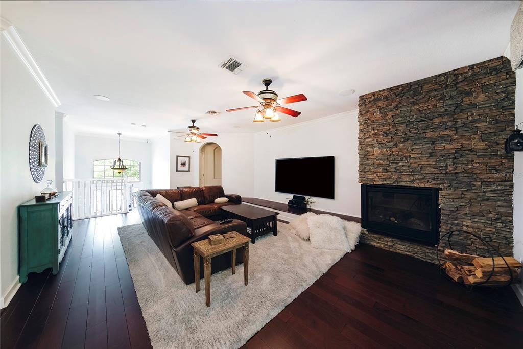 A living room features a stone fireplace, dark wood floors, and a brown leather sectional — 1397 LATTIMORE DRIVE, CLERMONT, FL