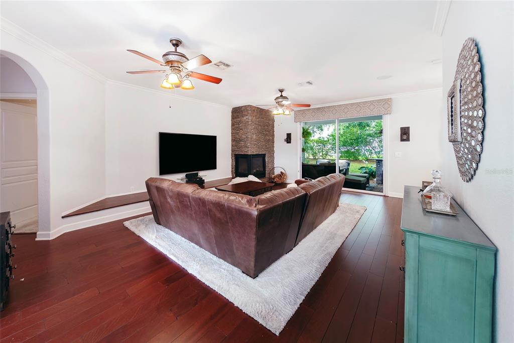 A living room features a brown leather sectional, stone fireplace, and dark wood flooring — 1397 LATTIMORE DRIVE, CLERMONT, FL