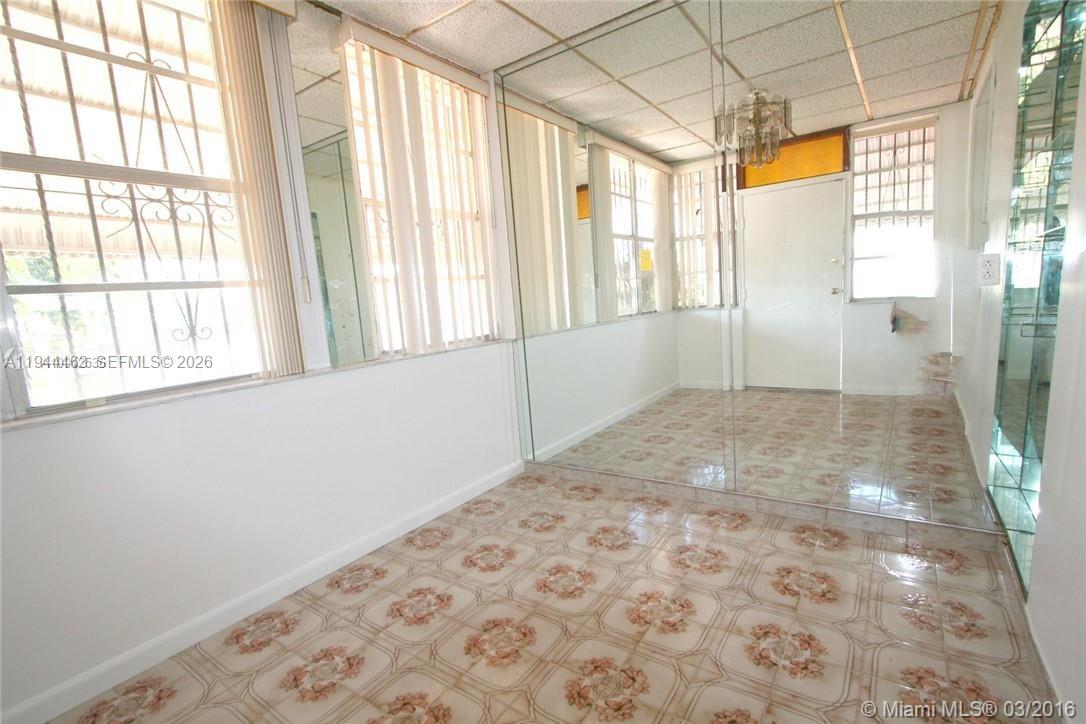 A sunroom features tiled flooring, mirrored walls, and a drop ceiling with a chandelier — 1119 SW 9th St, Miami FL 33130, MIAMI, FL