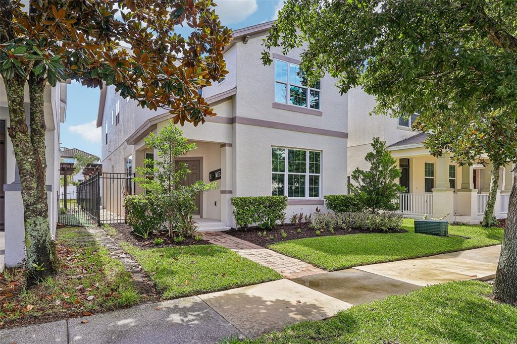 A two-story house with a light-colored stucco exterior, a brick walkway, and surrounding trees — 6412 GOLDEN DEWDROP TRAIL, WINDERMERE, FL