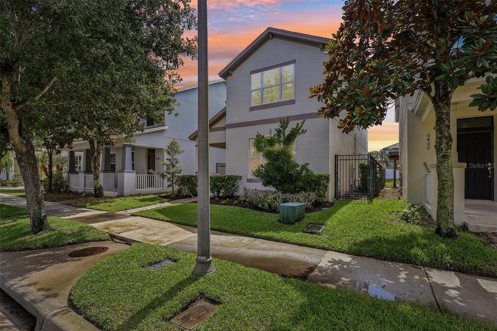 A two-story house with a light-colored exterior, a small front yard, and a metal fence — 6412 GOLDEN DEWDROP TRAIL, WINDERMERE, FL