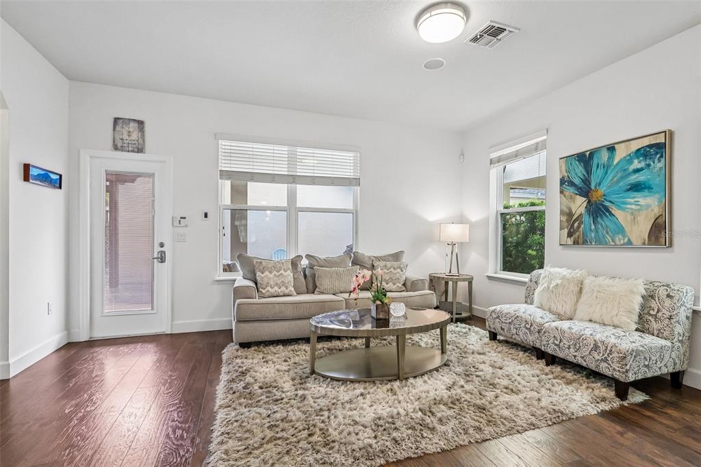 A living room features a beige sofa, patterned loveseat, round coffee table, and hardwood floors — 6412 GOLDEN DEWDROP TRAIL, WINDERMERE, FL