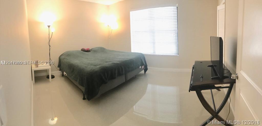 A bedroom features a large bed, a desk with a television, and light-colored tile flooring — 11447 SW 33rd Ln # 0, Miami FL 33165, MIAMI, FL