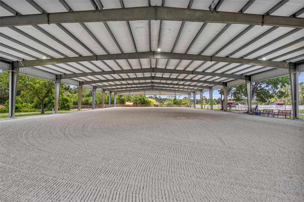 An expansive, covered outdoor equestrian riding arena with a raked sand surface and metal framing — 3287 N COUNTY ROAD 426, GENEVA, FL