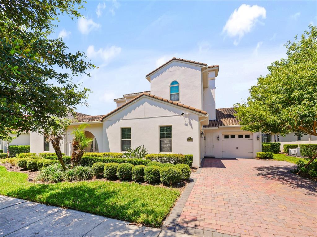 A two-story stucco house with a tiled roof, arched window, and brick driveway — 15704 MARINA BAY DRIVE, WINTER GARDEN, FL