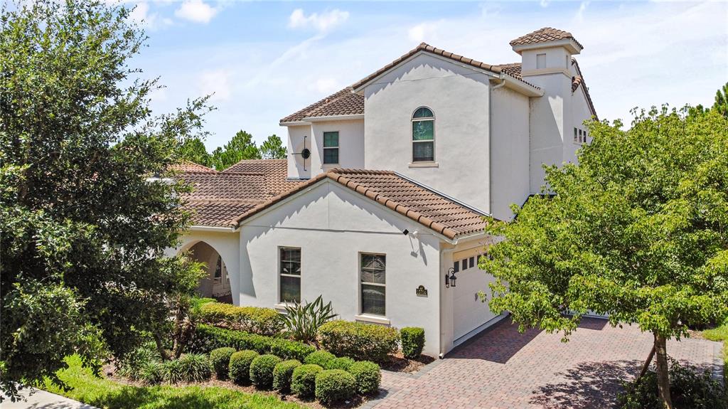 A two-story stucco house with a tiled roof, arched entryway, and a brick paver driveway — 15704 MARINA BAY DRIVE, WINTER GARDEN, FL