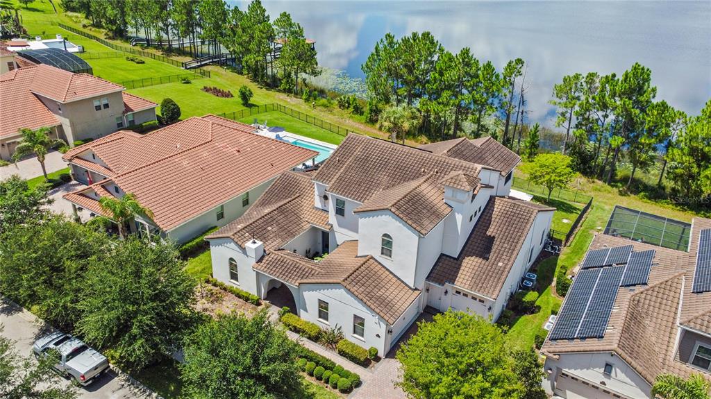 An aerial view shows a large white house with a brown tile roof near a lake — 15704 MARINA BAY DRIVE, WINTER GARDEN, FL