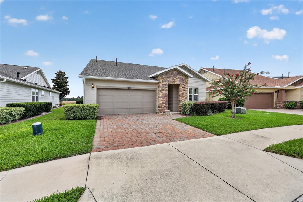 A single-story house with a stone facade, beige siding, and a paved driveway — 4967 NW 35TH LANE ROAD, OCALA, FL