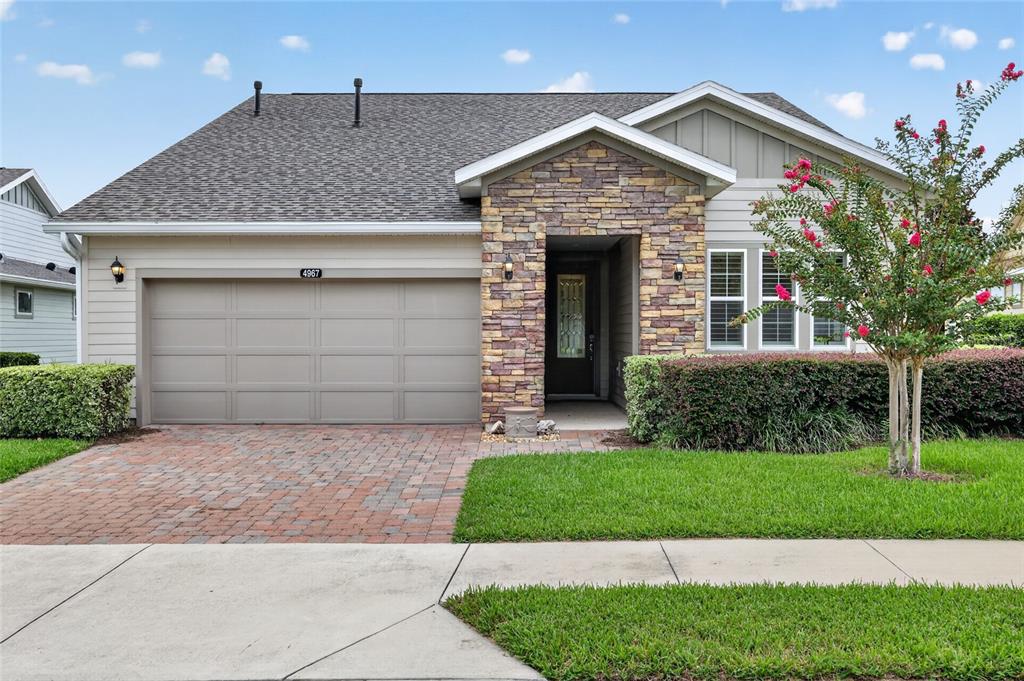 A single-story house features a stone-accented entryway, a two-car garage, and a landscaped front yard — 4967 NW 35TH LANE ROAD, OCALA, FL