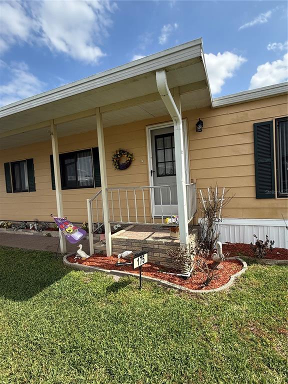 The exterior of a tan mobile home features a covered porch with a metal railing — 2055 S FLORAL AVENUE UNIT 175, BARTOW, FL
