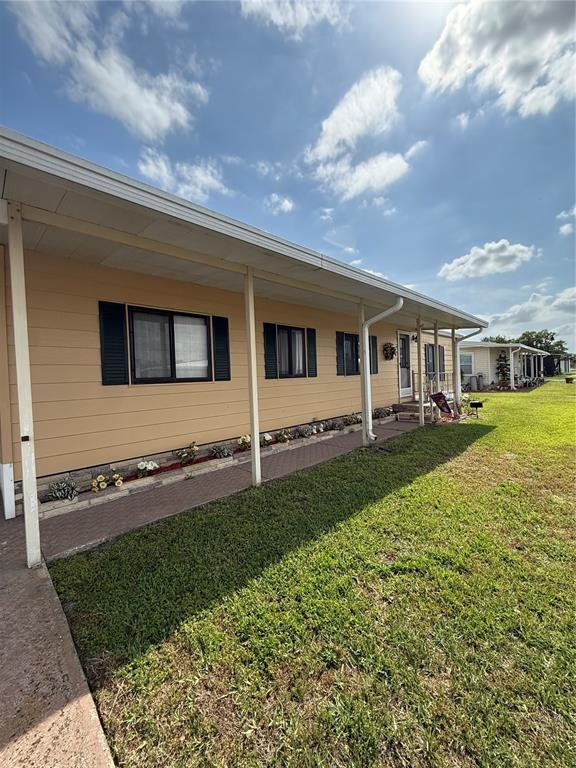 A tan mobile home features a covered porch, dark shutters, and a brick-lined flower bed — 2055 S FLORAL AVENUE UNIT 175, BARTOW, FL
