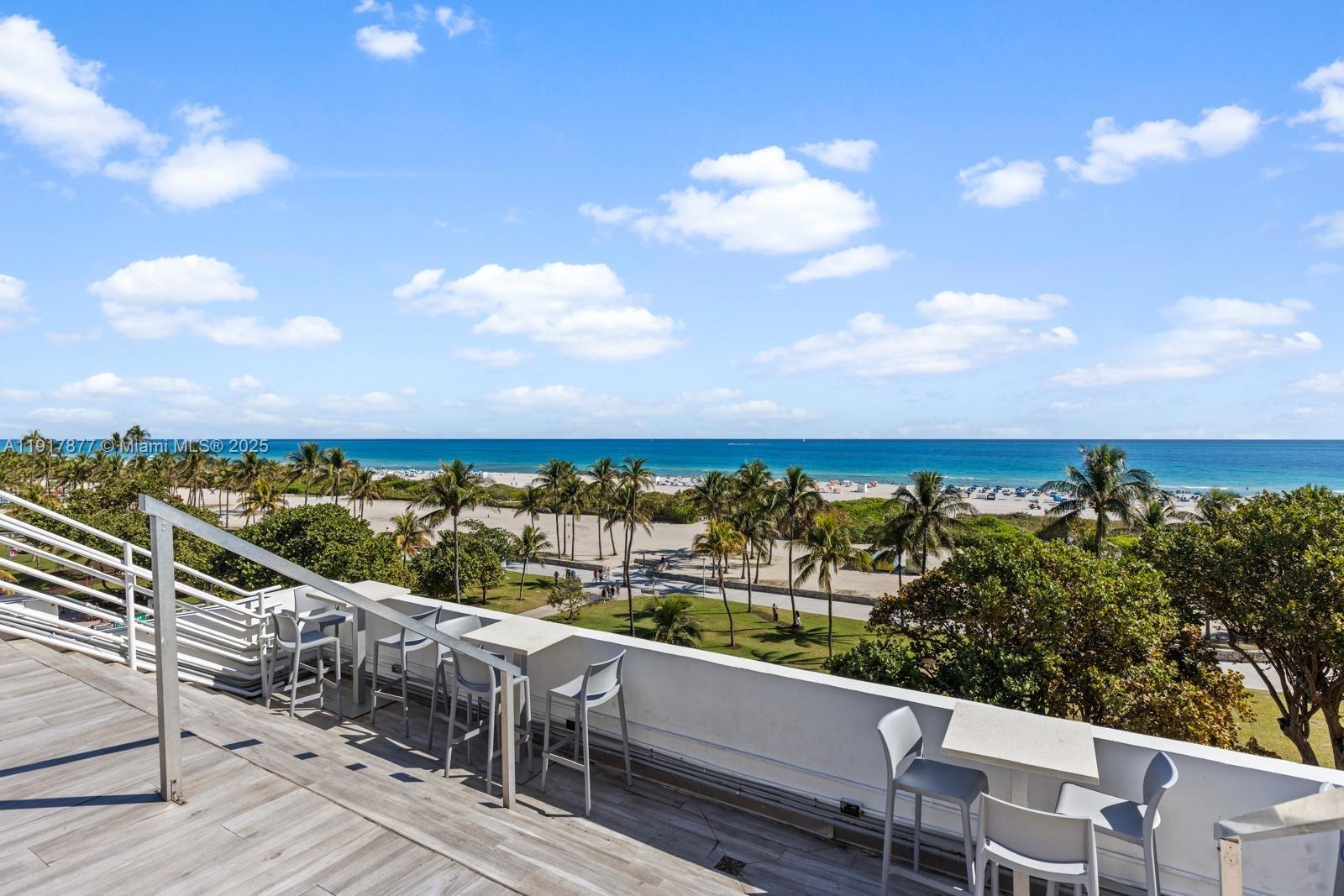 An outdoor balcony features bar-style seating overlooking a sandy beach and the ocean — 1024 Ocean Dr # A502, Miami Beach FL 33139, MIAMI BEACH, FL