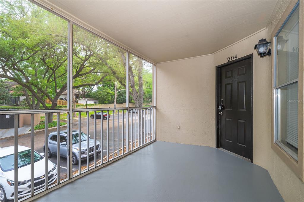 A screened-in balcony features a gray floor, a dark brown door, and a metal railing — 623 DORY LANE UNIT 204, ALTAMONTE SPRINGS, FL