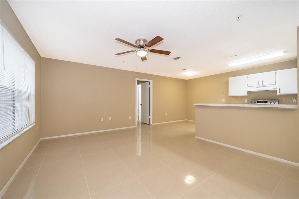 An open-concept living area features beige walls, light-colored tile flooring, and a kitchen breakfast bar — 623 DORY LANE UNIT 204, ALTAMONTE SPRINGS, FL